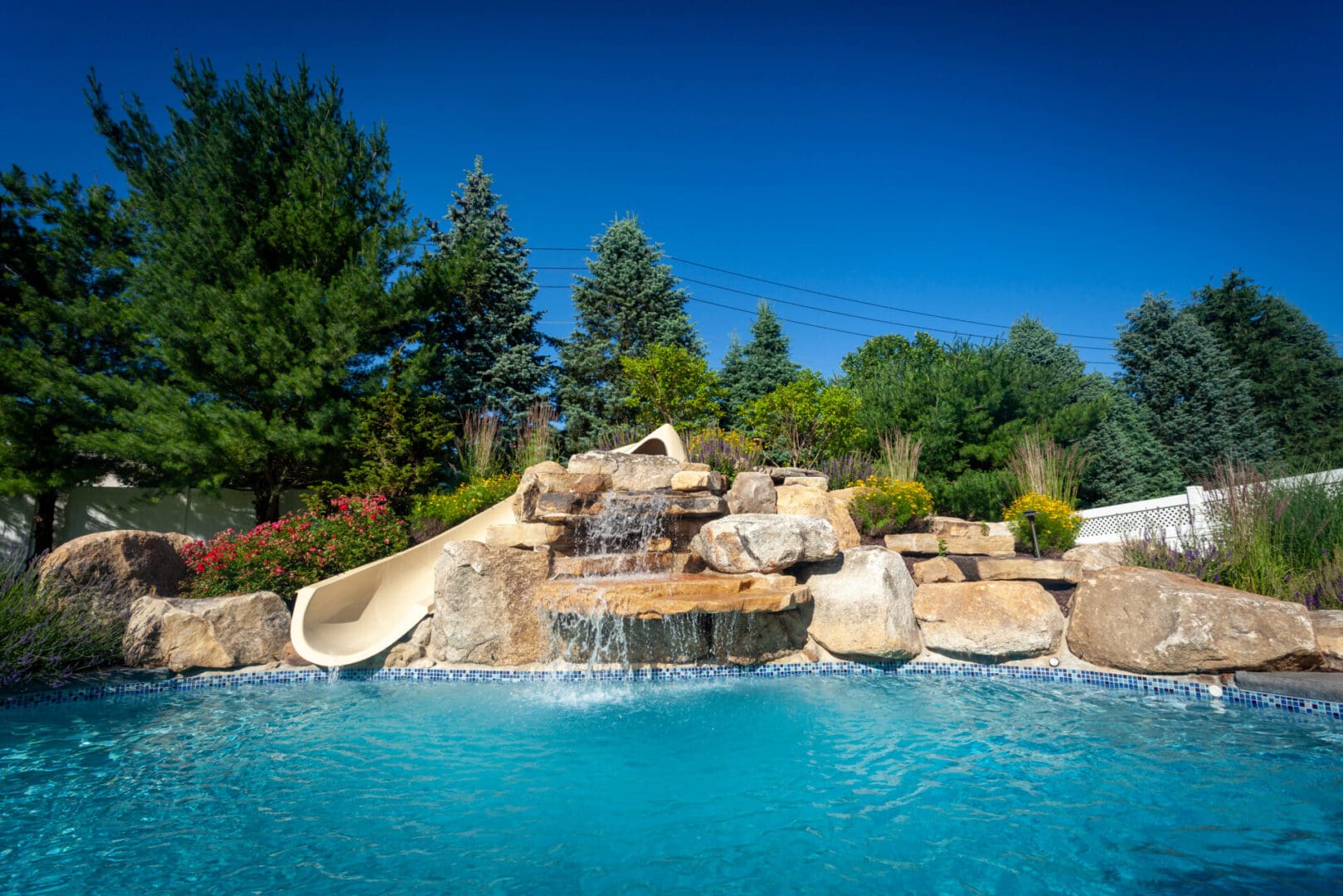 A pool with water slides and rocks in the background.