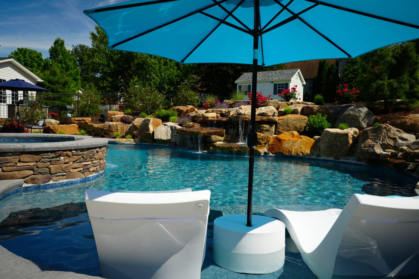 A pool with an umbrella and chairs in it