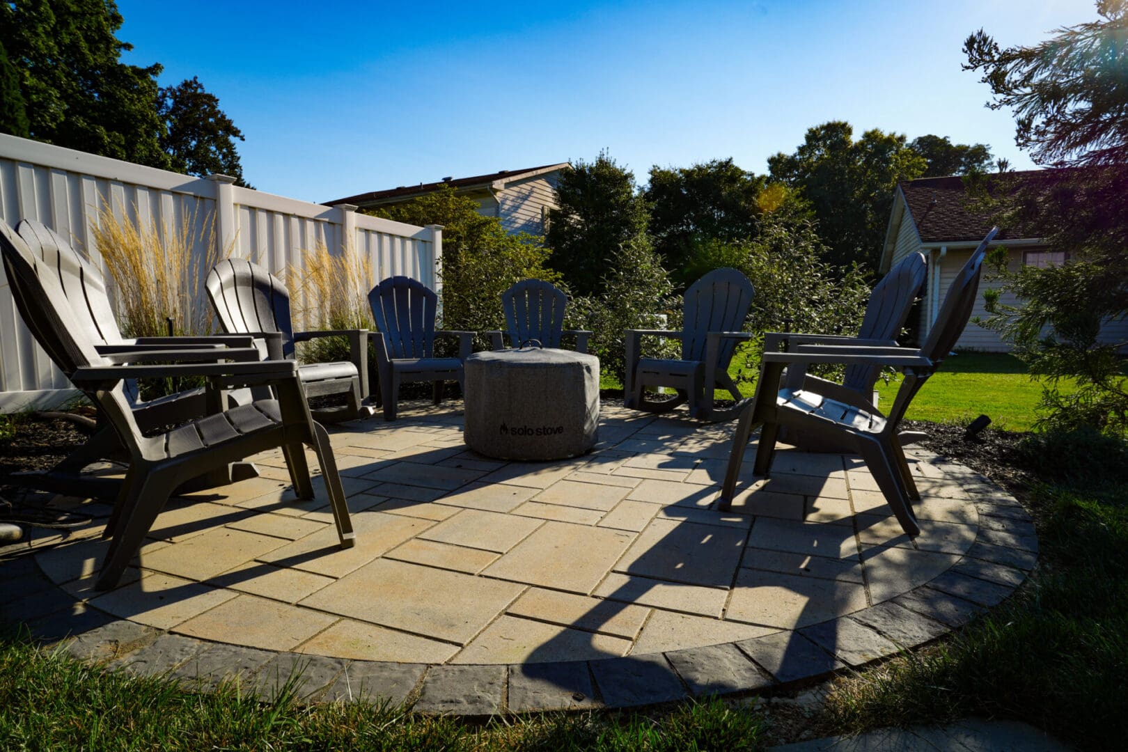 A patio with chairs and fire pit in the middle of it.