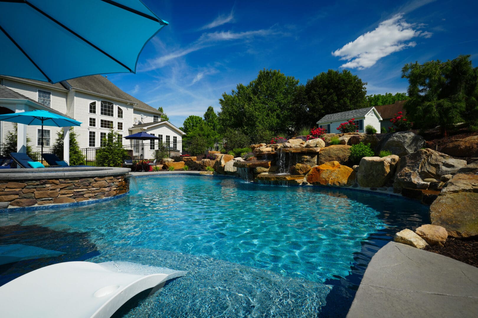 A pool with a waterfall and a large rock wall.