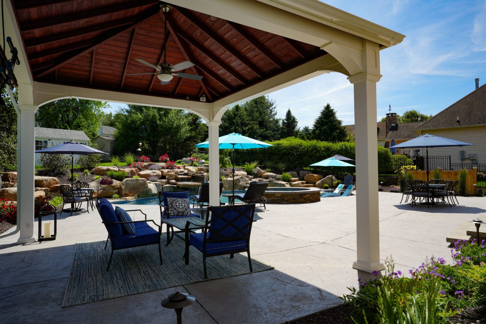 A patio with chairs and umbrellas in the shade.