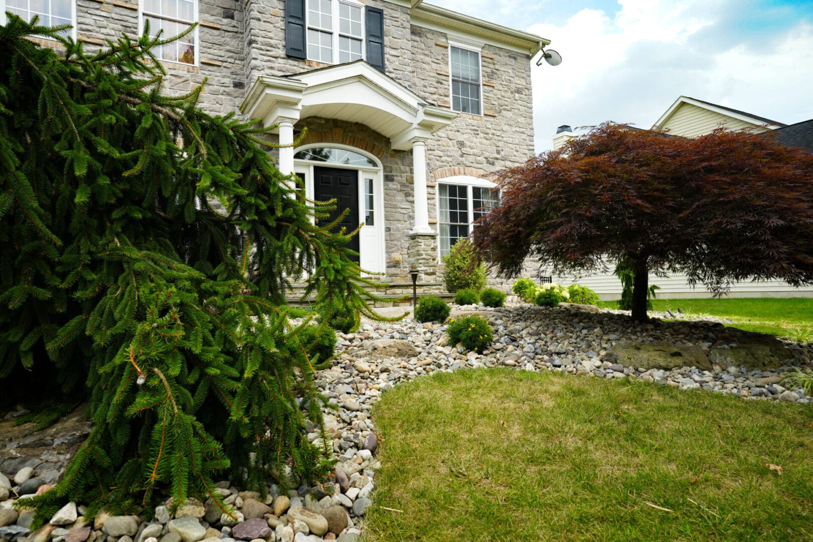 A house with rocks and bushes in front of it