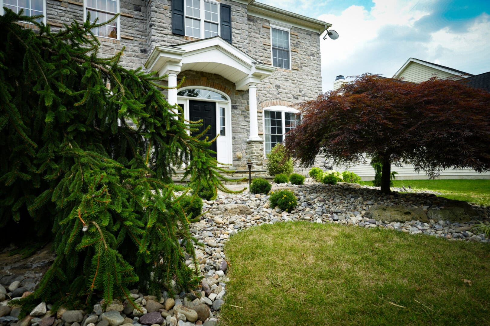 A house with rocks and bushes in front of it