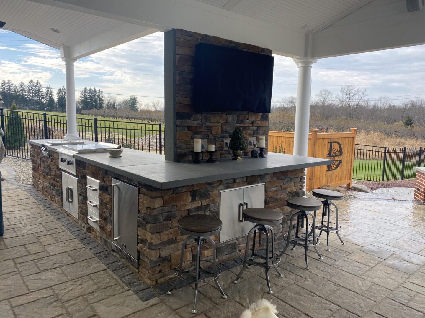 A large outdoor kitchen with an entertainment center.