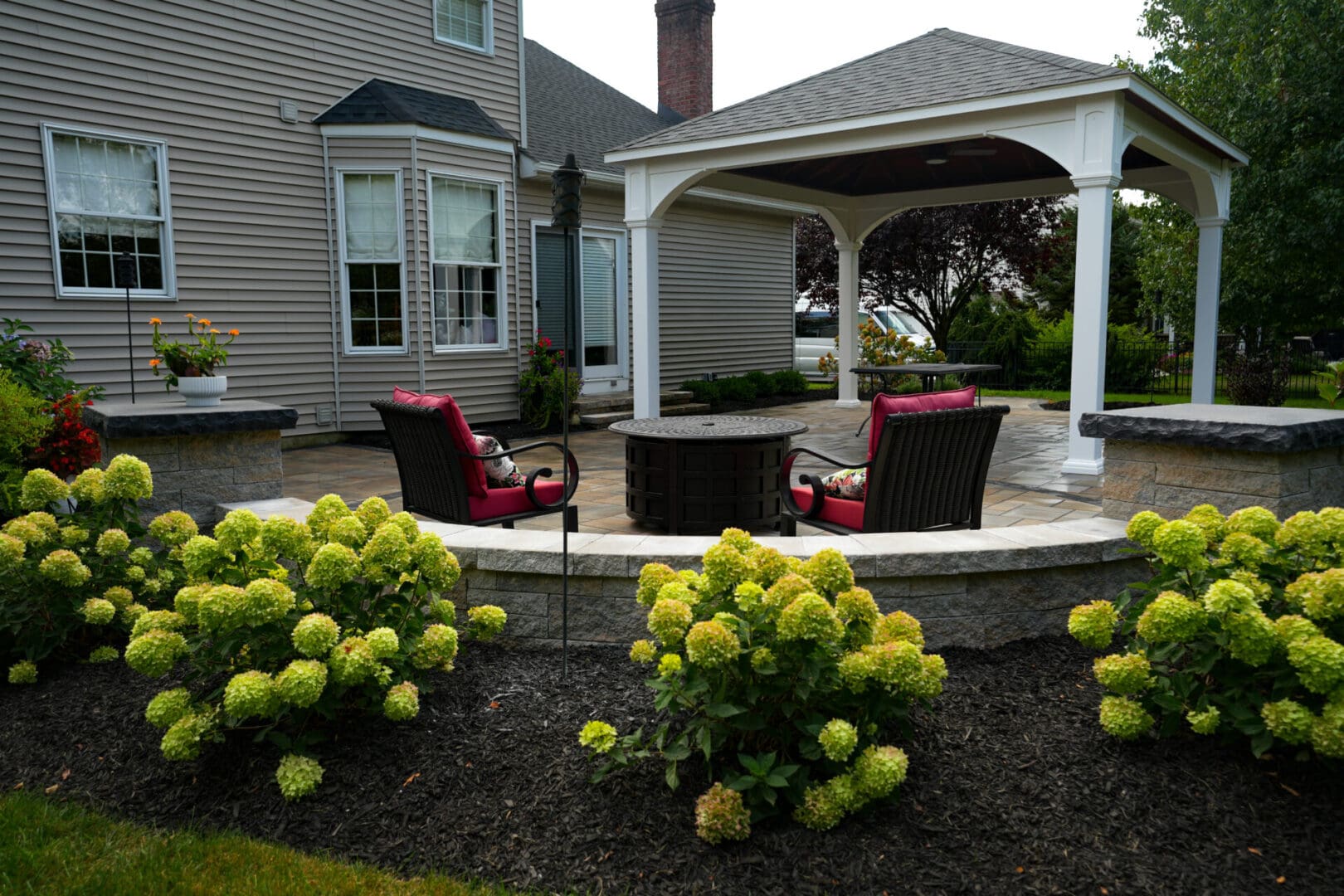 A patio with chairs and flowers in the middle of it