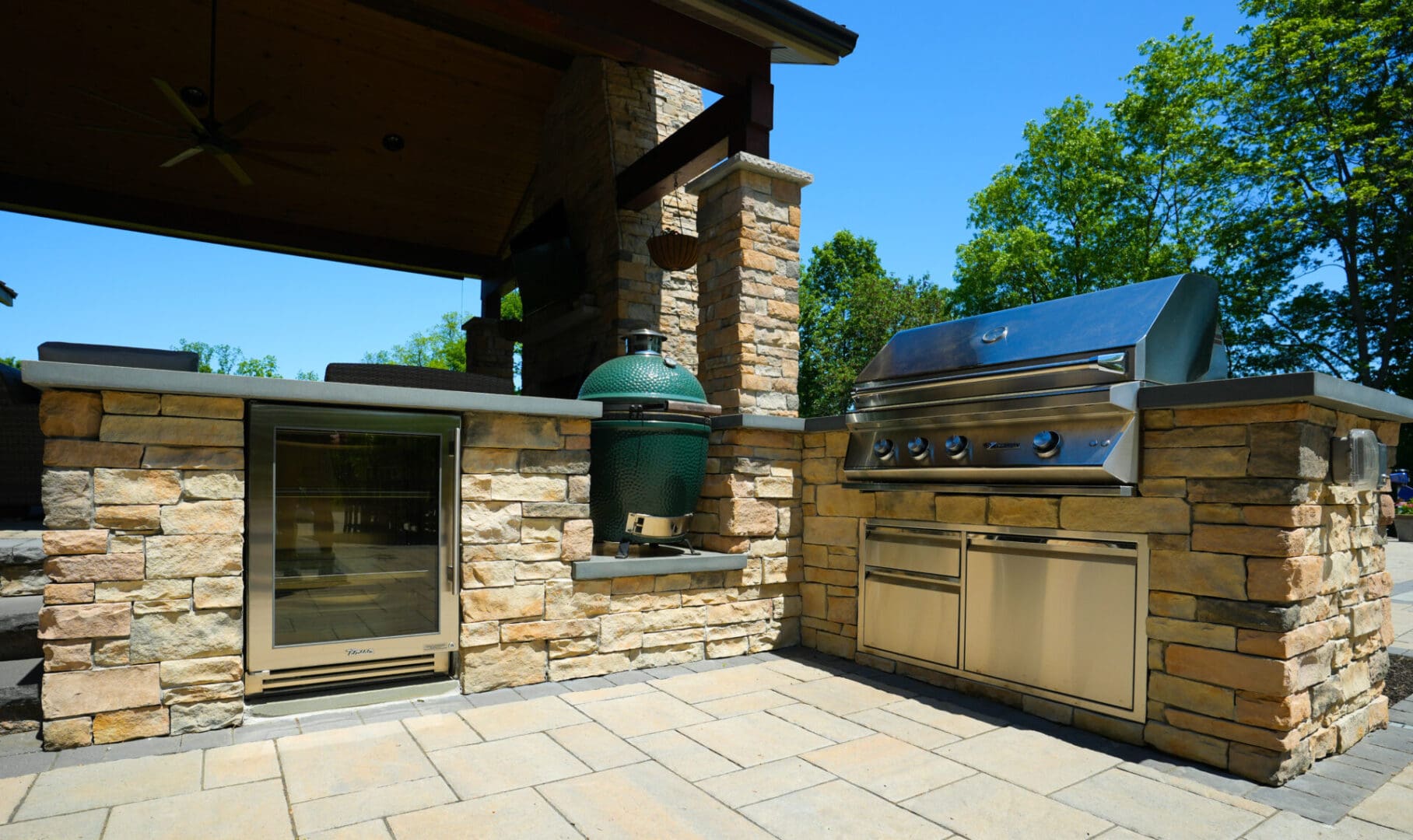 A large outdoor grill with an oven and a big green egg.